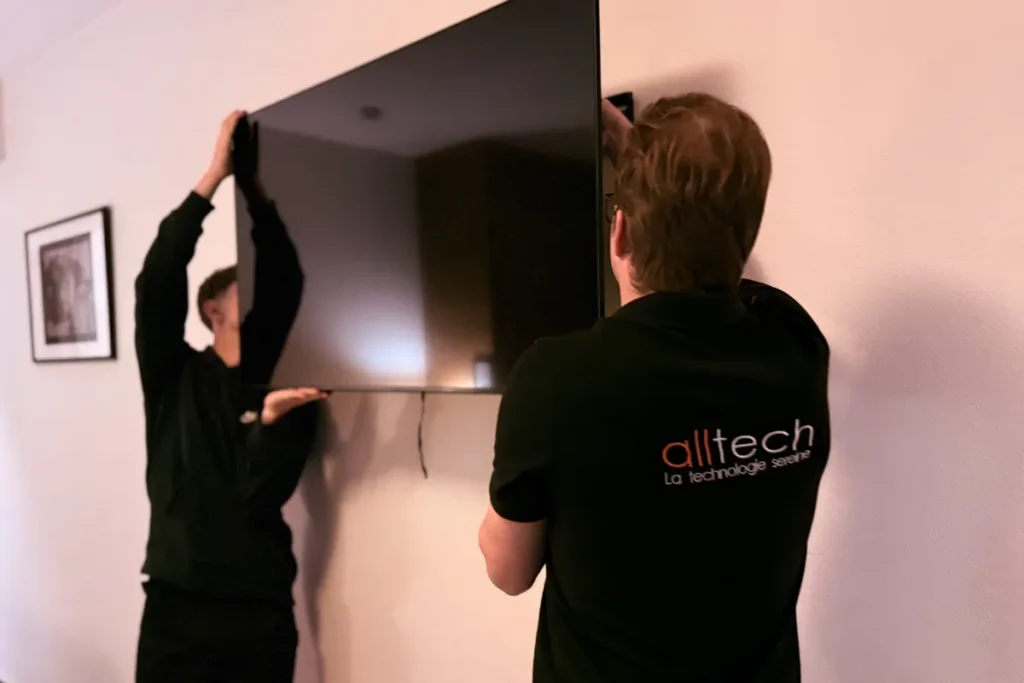 Deux techniciens Alltech fixent un téléviseur dans une chambre d’hôtel